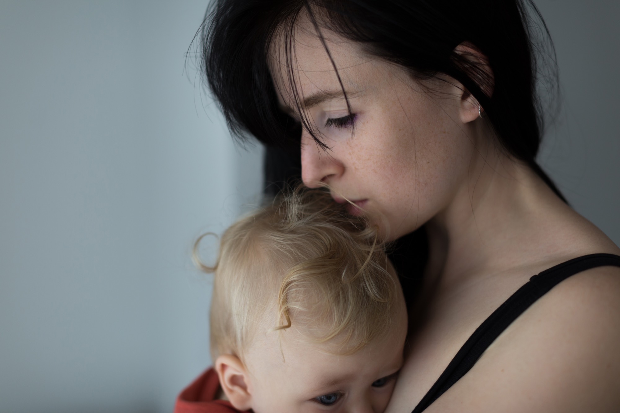 A mother kisses her toddler's head.